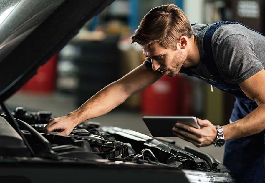 A mechanic checking the performance of the car while a tablet to make changes after.