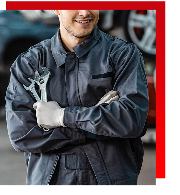 Cropped image of mechanic posing while holding two different wrenches on one hand.